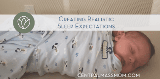 sleeping baby wrapped in a swaddle laying in a bassinette