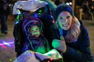 A mother and her young child, sitting in a stroller, are smiling at the camera