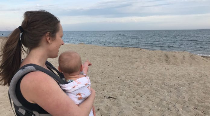 mom on the beach baby wearing her infant