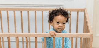 toddler standing in his crib, not sleeping because he is ready to drop naps