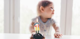 a child sitting in front of a first birthday cupcake