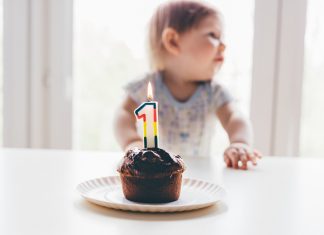 a child sitting in front of a first birthday cupcake