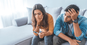a man and woman looking at a pregnancy test struggling with infertility