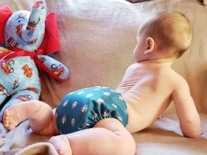 Infant crawling wearing just a cloth diaper, green with octopus pattern on it.