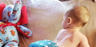 Infant crawling wearing just a cloth diaper, green with octopus pattern on it.