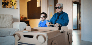 adult and child find creative ways to reuse cardboard boxes, by making it into a car.