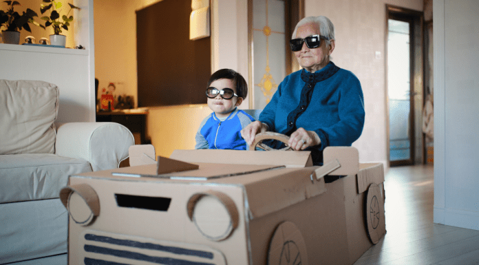 adult and child find creative ways to reuse cardboard boxes, by making it into a car.
