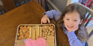 little girl smiling next to her super easy valentine's dessert board