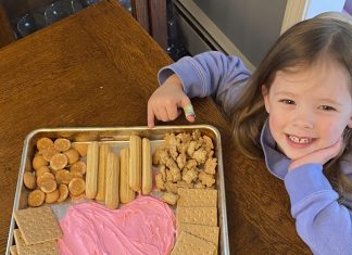 little girl smiling next to her super easy valentine's dessert board