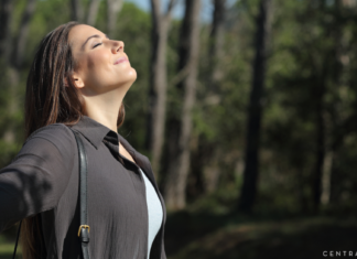 woman taking in a deep calming breath outdoors facing into the sunlight
