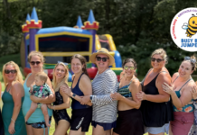group of moms standing in a line with an inflatable rental bouncy house behind them