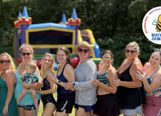 group of moms standing in a line with an inflatable rental bouncy house behind them