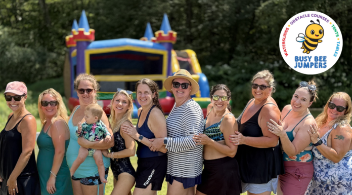 group of moms standing in a line with an inflatable rental bouncy house behind them