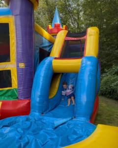 little boy sliding down the slide of an inflatable rental bounce house