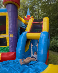 mom sliding down the slide of an inflatable rental bounce house
