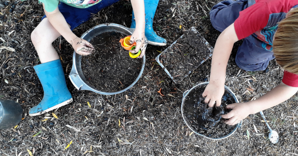 2 kids playing in the dirt with buckets for an inexpensive at-home spring break activity